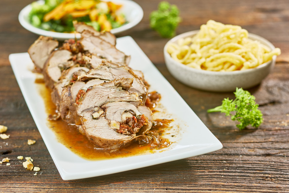 Gef&uuml;llte Fleischrolade mit So&szlig;e, Nudeln und Gem&uuml;sebeilage auf Holztisch, Food-Fotografie, Foto: Oliver Giel